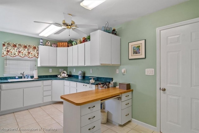 kitchen featuring ceiling fan, sink, white cabinets, and light tile patterned floors