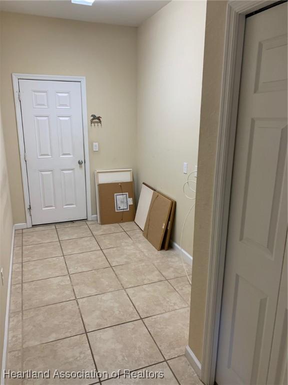 laundry area with light tile patterned floors and baseboards