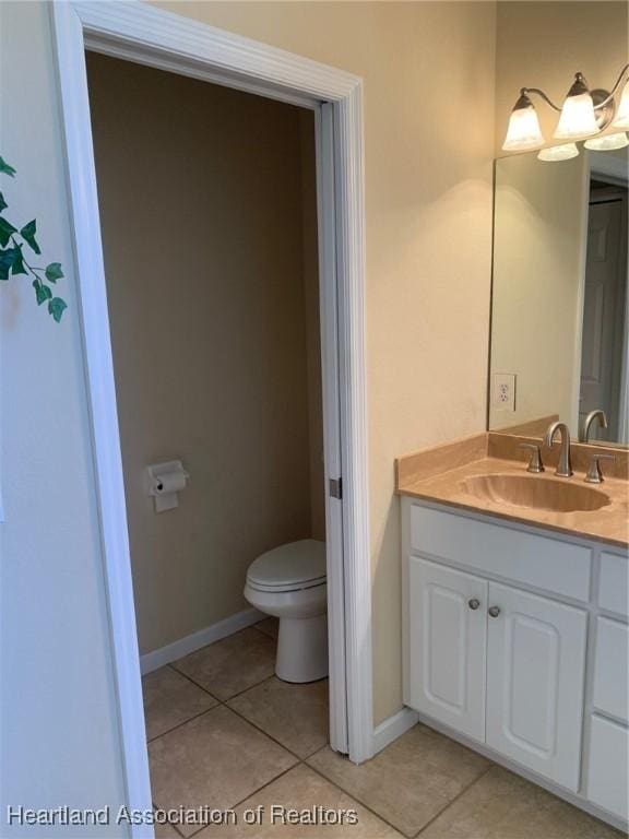 bathroom featuring toilet, vanity, baseboards, and tile patterned floors