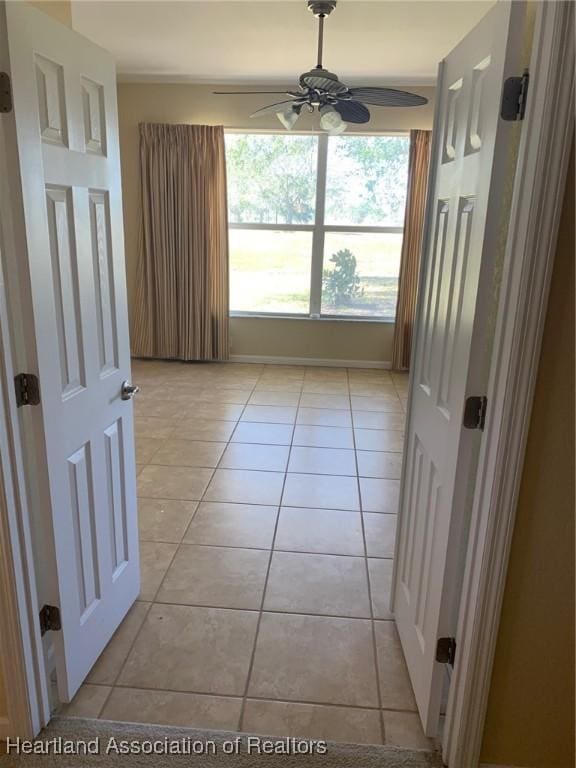 empty room with ceiling fan and light tile patterned floors