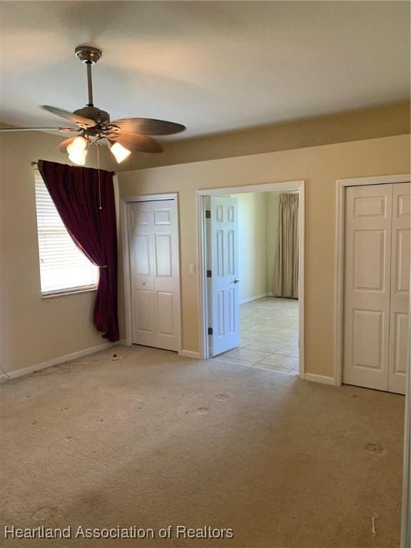 unfurnished bedroom with baseboards, a ceiling fan, and light colored carpet