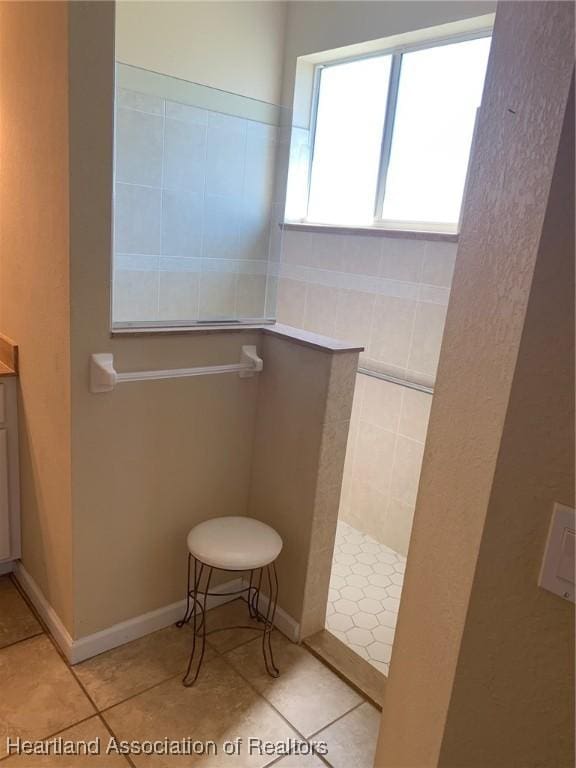 bathroom featuring tile patterned flooring, baseboards, and walk in shower