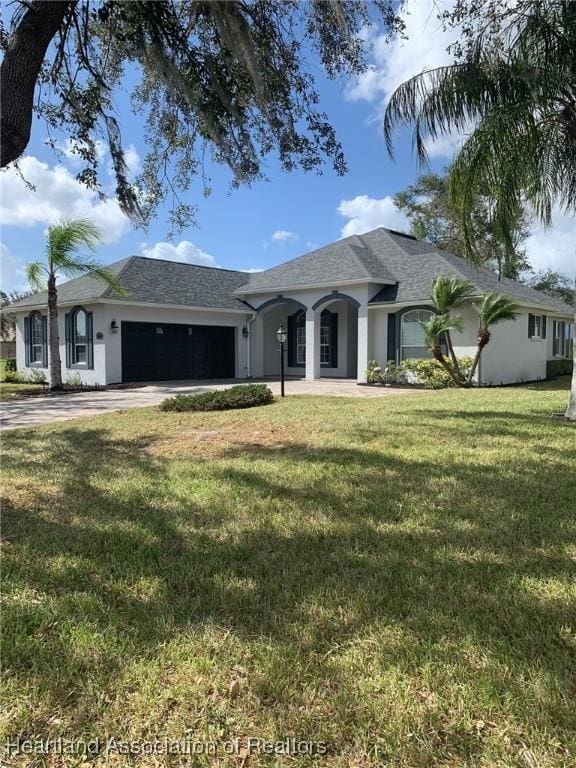 ranch-style home featuring concrete driveway, a front lawn, an attached garage, and stucco siding