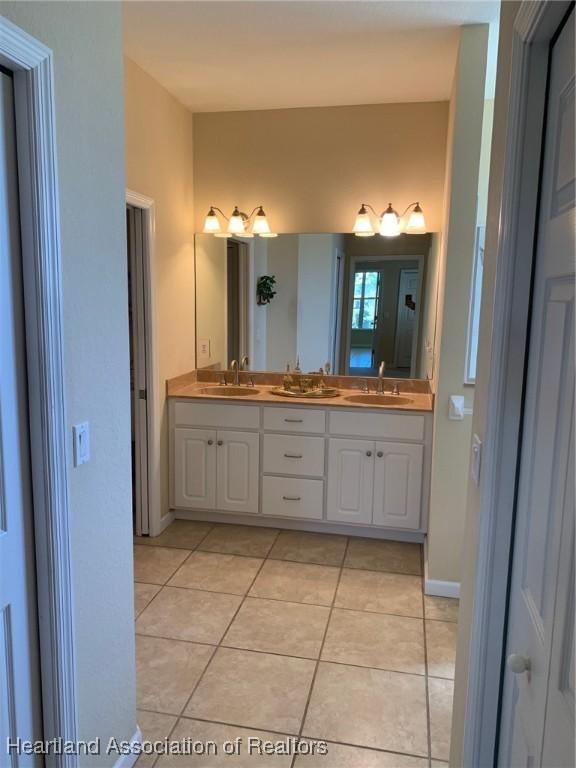 full bathroom featuring tile patterned flooring, a sink, baseboards, and double vanity