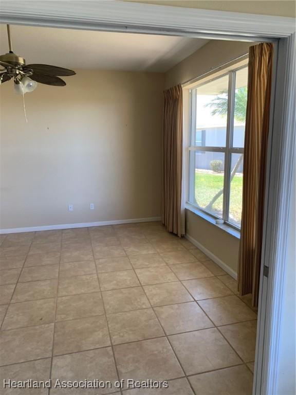 empty room with light tile patterned floors, baseboards, and a ceiling fan