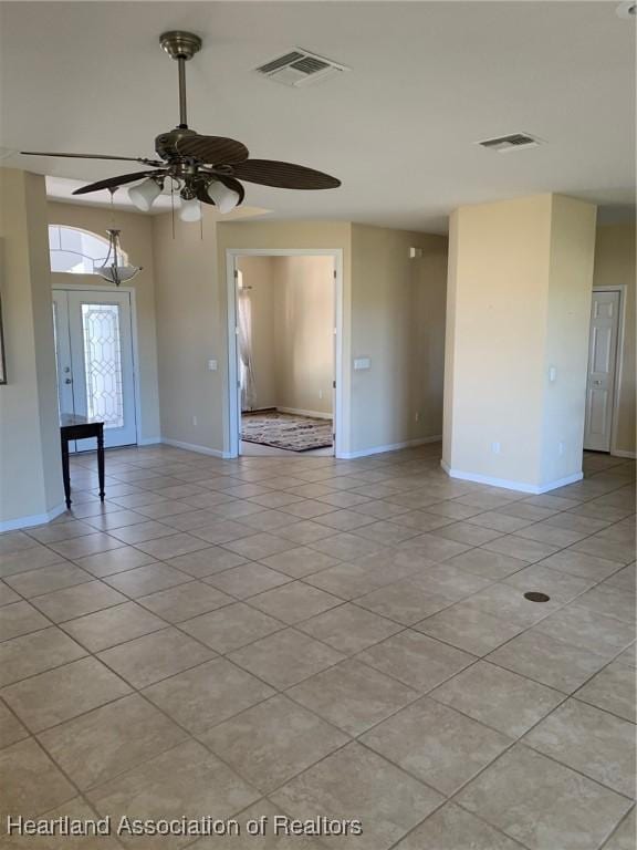 empty room featuring light tile patterned floors, baseboards, visible vents, and ceiling fan