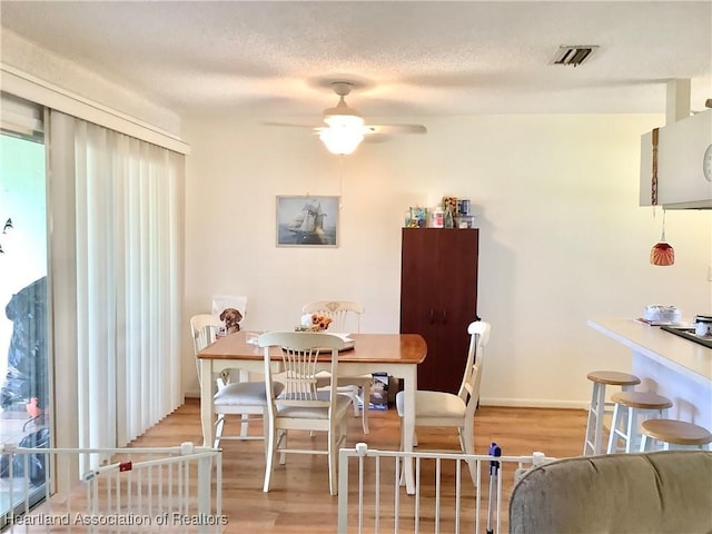 dining area featuring ceiling fan, a textured ceiling, and light wood-type flooring