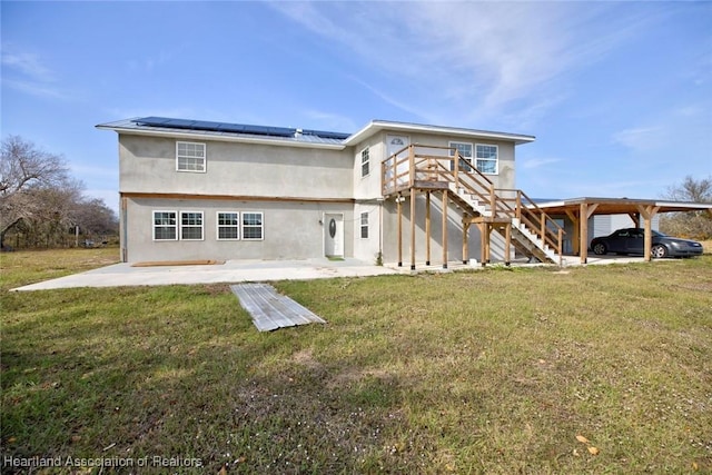 rear view of property featuring a patio area, a lawn, and solar panels