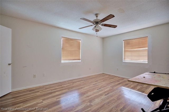 spare room with light hardwood / wood-style floors, a textured ceiling, and ceiling fan