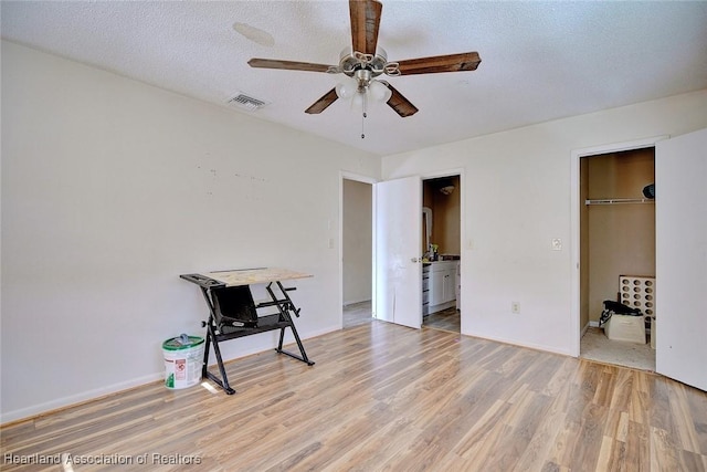 interior space featuring ensuite bathroom, light hardwood / wood-style floors, a spacious closet, a textured ceiling, and a closet