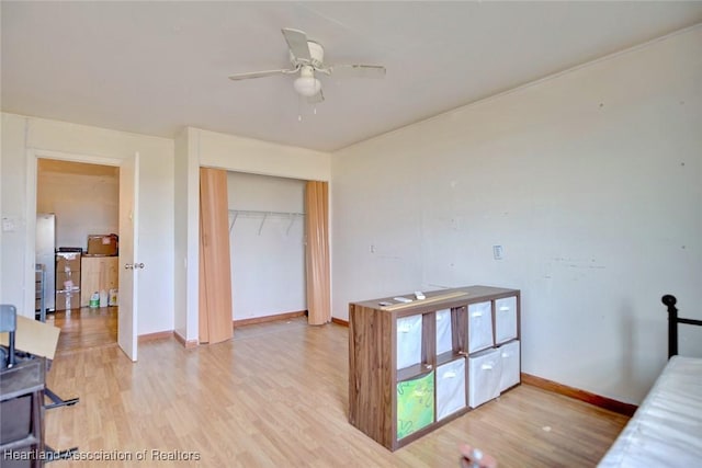 bedroom featuring a closet, ceiling fan, light hardwood / wood-style flooring, and stainless steel refrigerator