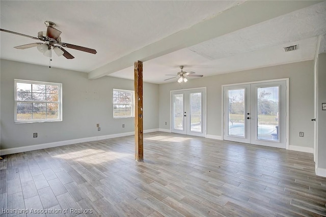 spare room with ceiling fan, light hardwood / wood-style flooring, beam ceiling, and french doors