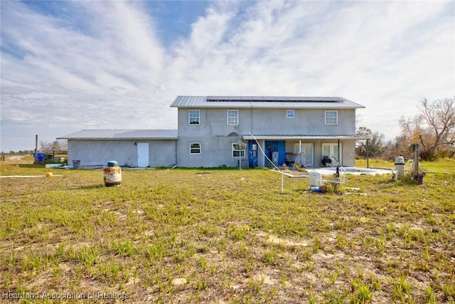 back of property featuring a lawn, solar panels, and a patio