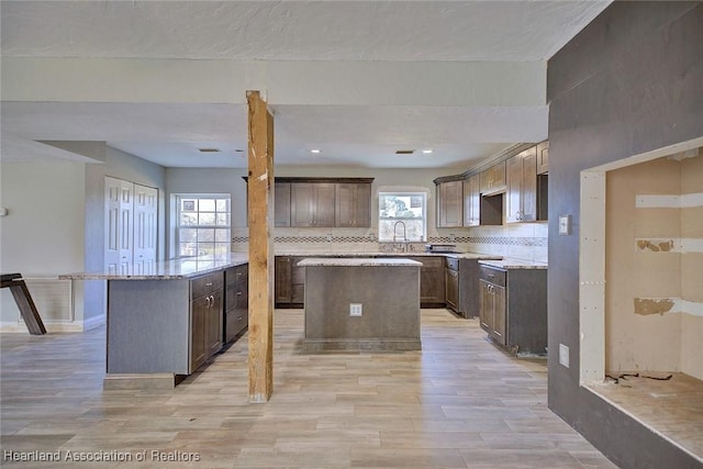 kitchen with tasteful backsplash, plenty of natural light, dark brown cabinets, and a center island