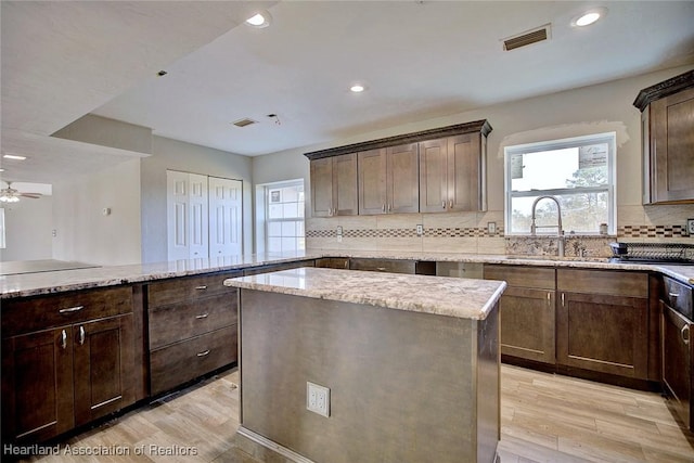 kitchen featuring a center island, tasteful backsplash, sink, ceiling fan, and light hardwood / wood-style flooring