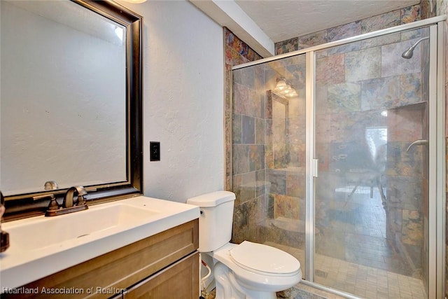 bathroom with a shower with shower door, toilet, and vanity