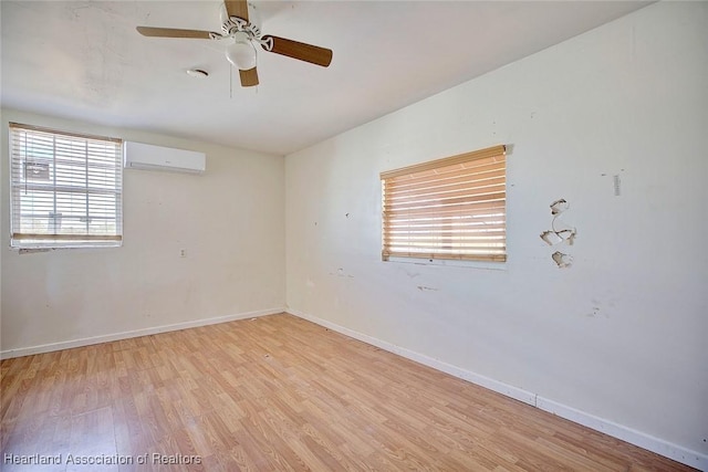 empty room with ceiling fan, a wall mounted AC, and light hardwood / wood-style flooring