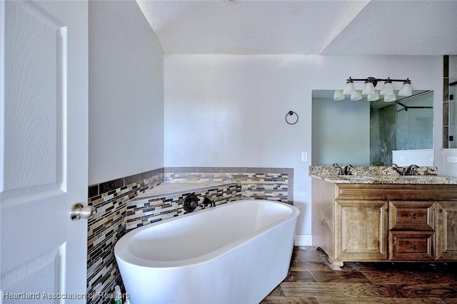 bathroom featuring a textured ceiling, a bathing tub, tile walls, and vanity