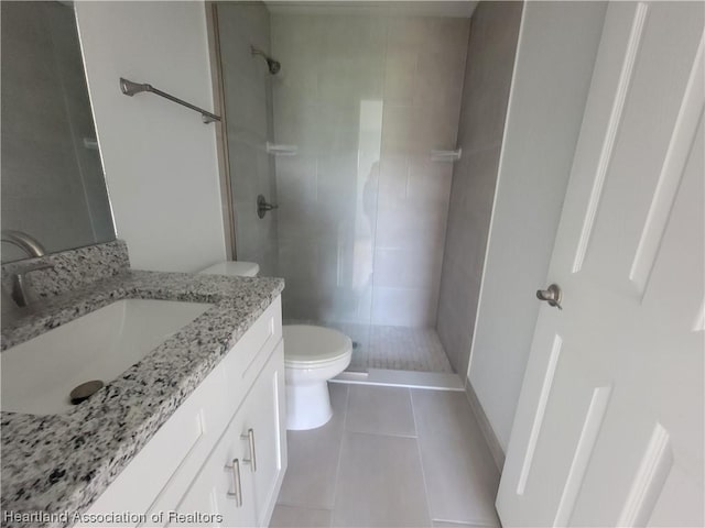 bathroom with tile patterned floors, toilet, vanity, and tiled shower