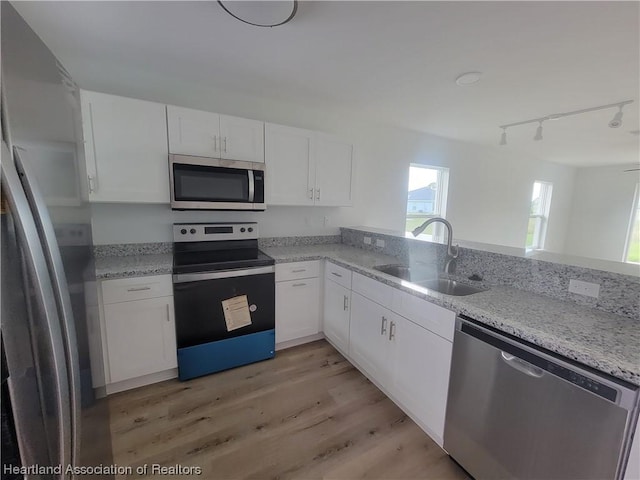 kitchen with sink, stainless steel appliances, kitchen peninsula, track lighting, and white cabinets