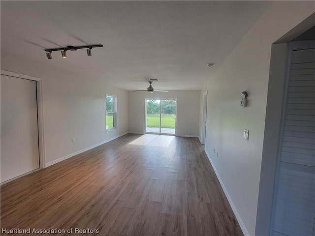 empty room with track lighting, ceiling fan, and light hardwood / wood-style floors