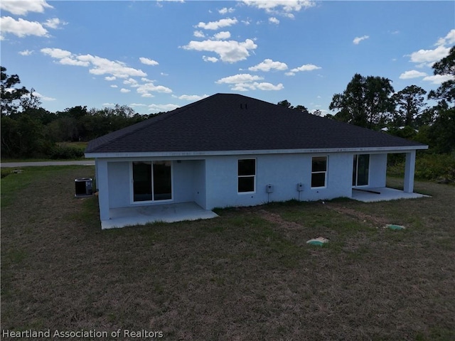 rear view of house with cooling unit, a patio area, and a lawn