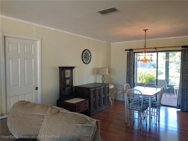 dining area featuring dark hardwood / wood-style floors, ornamental molding, and an inviting chandelier