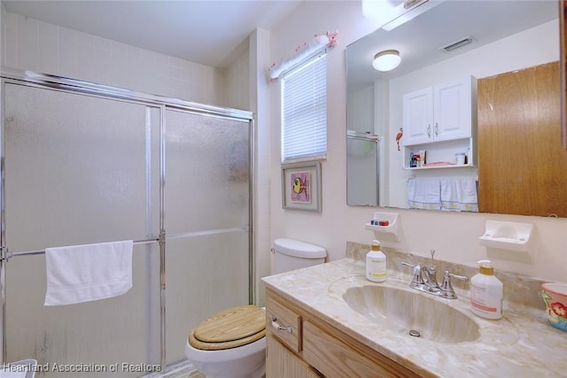 bathroom featuring vanity, toilet, and a shower with door