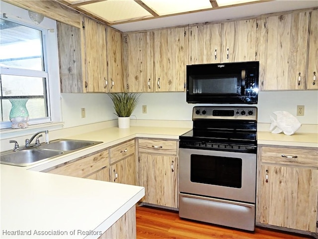 kitchen with light brown cabinetry, sink, light hardwood / wood-style floors, and stainless steel electric range