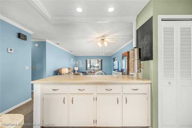 kitchen featuring crown molding, ceiling fan, carpet floors, white cabinets, and kitchen peninsula