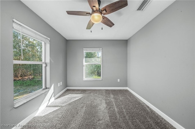 empty room featuring a healthy amount of sunlight, ceiling fan, and carpet flooring