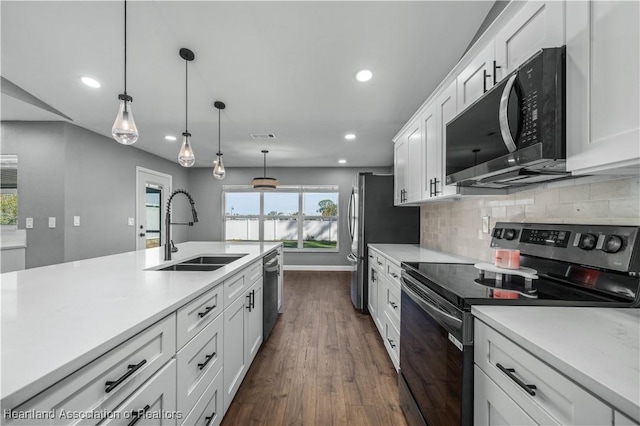 kitchen with stainless steel appliances, sink, white cabinets, and decorative light fixtures