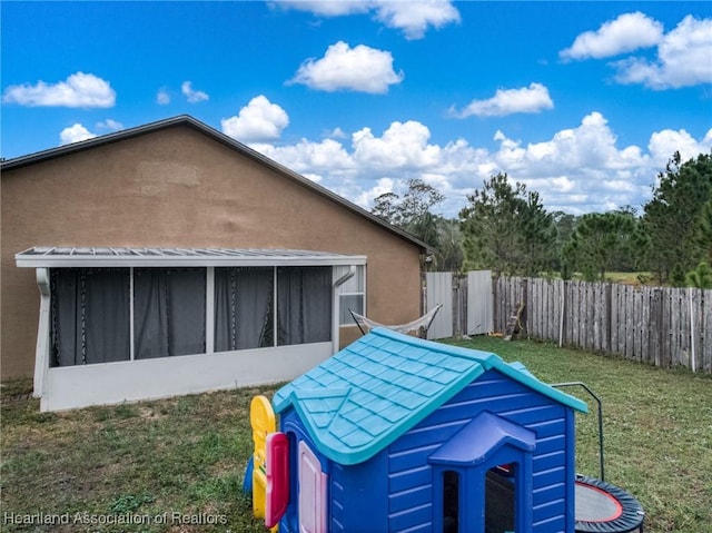 view of side of home featuring a yard, fence, a sunroom, and stucco siding