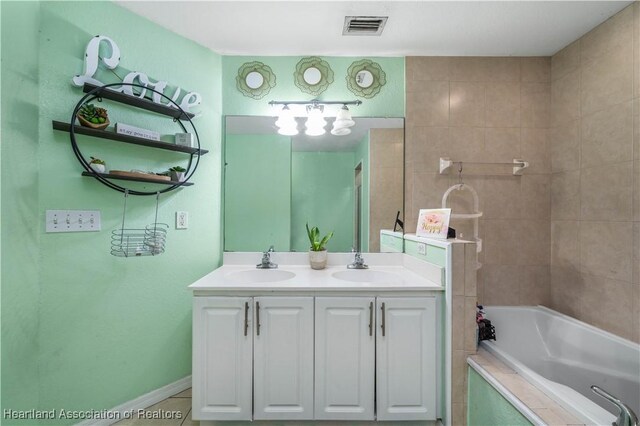 full bathroom featuring tiled bath, visible vents, double vanity, and a sink