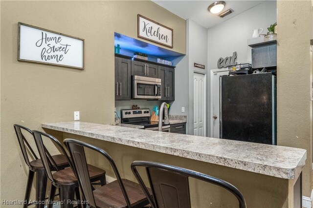 kitchen with visible vents, a breakfast bar, stainless steel appliances, a peninsula, and light countertops