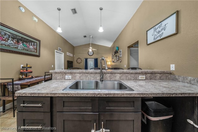 kitchen featuring visible vents, dark brown cabinets, pendant lighting, vaulted ceiling, and a sink