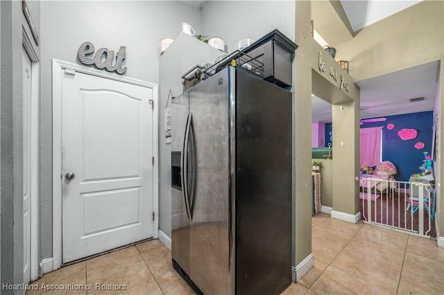 kitchen featuring light tile patterned floors, baseboards, stainless steel fridge, and visible vents