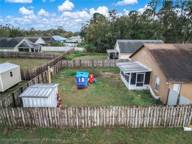 view of yard featuring an outdoor structure, a fenced backyard, and a sunroom