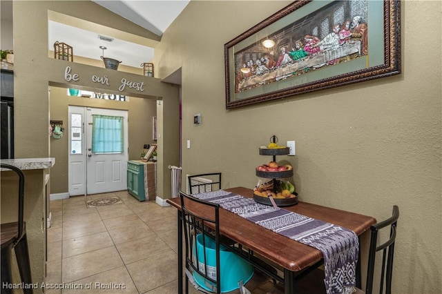 dining space with lofted ceiling, light tile patterned floors, visible vents, and baseboards