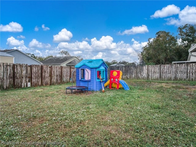 view of playground with an outbuilding, a lawn, and a fenced backyard