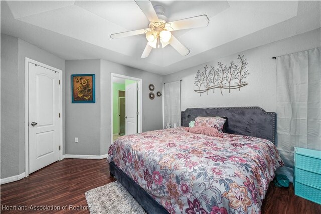 bedroom with a ceiling fan, wood finished floors, and baseboards