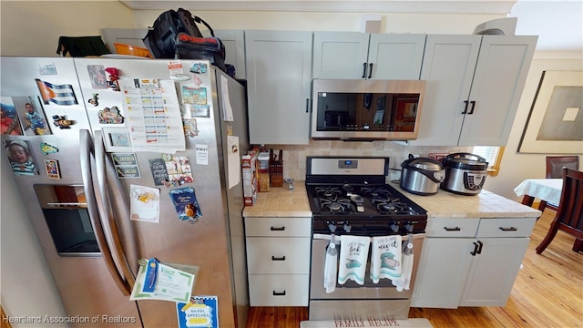 1102 W Gibson St, Arcadia, FL 34266 - kitchen featuring appliances with stainless steel finishes, light countertops, light wood-style flooring, and backsplash