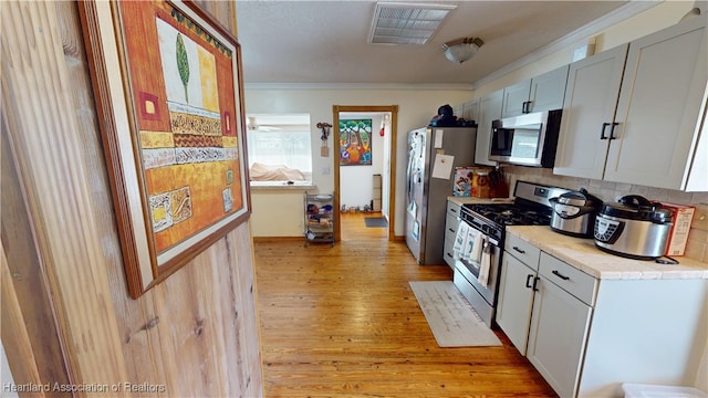 1102 W Gibson St, Arcadia, FL 34266 - kitchen featuring stainless steel appliances, ornamental molding, light wood-style flooring, light countertops, and decorative backsplash