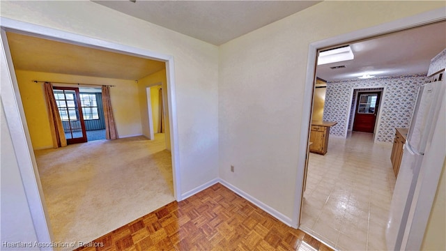 hall featuring visible vents, baseboards, and wallpapered walls