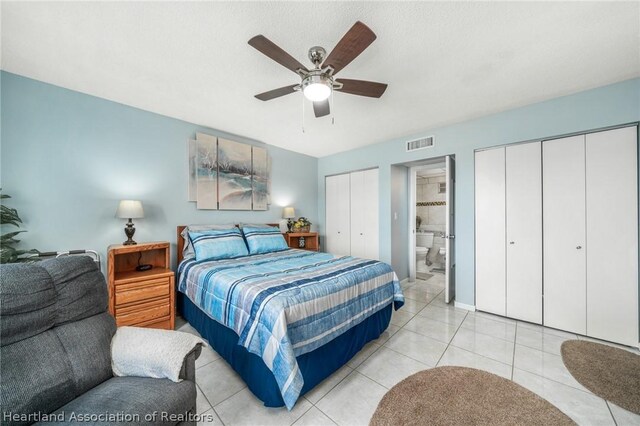 tiled bedroom featuring ensuite bathroom, ceiling fan, and multiple closets