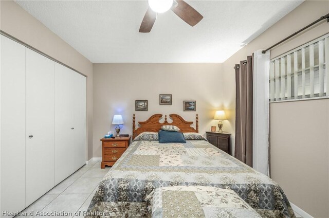 bedroom featuring ceiling fan, a closet, light tile patterned floors, and a textured ceiling