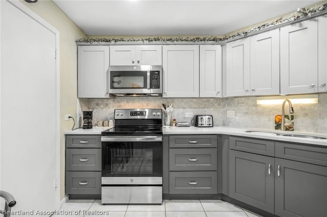 kitchen featuring decorative backsplash, gray cabinetry, stainless steel appliances, sink, and light tile patterned floors