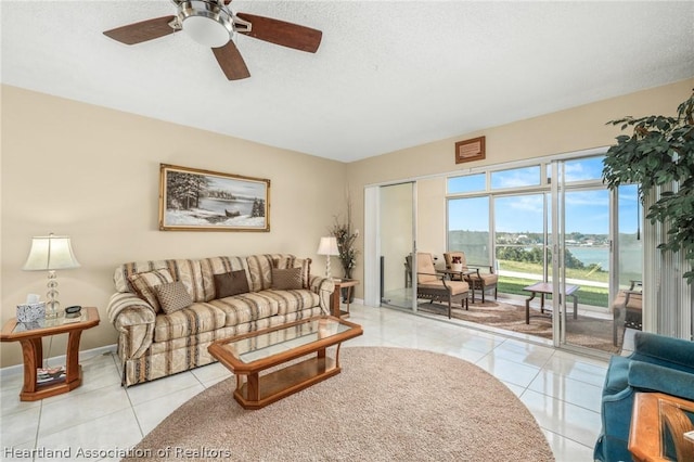 tiled living room with ceiling fan and a water view