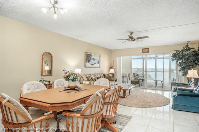 dining room with ceiling fan with notable chandelier, light tile patterned floors, and a textured ceiling