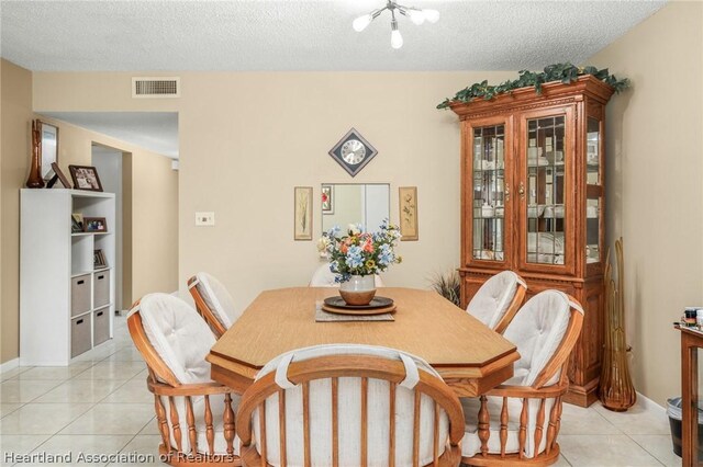 dining space with light tile patterned flooring, a chandelier, and a textured ceiling